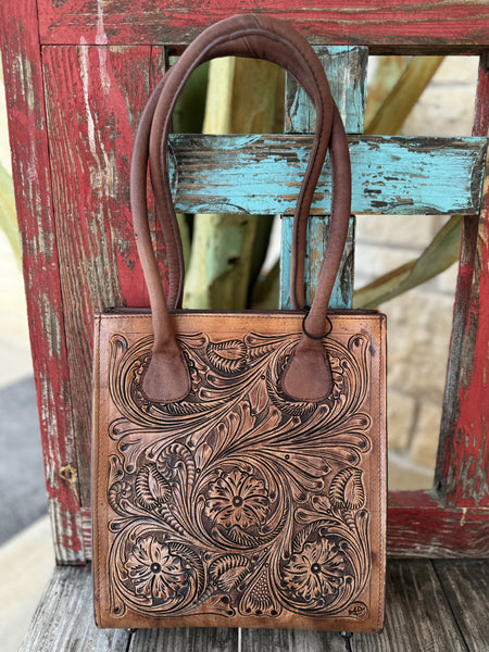 ADBGZ456 — Women's rich tan genuine leather structured tote purse with deep full-coverage floral and scroll hand-tooling, large central daisy/sunflower motif with sweeping acanthus leaf scrollwork and dark brown antiqued contrast, and two sturdy dark brown rounded loop leather top handles — Blair's Western Wear Marble Falls TX