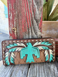 Women's brown tooled leather zip wallet with raised turquoise thunderbird-inspired figure, turquoise and white painted feather wings, and cream whipstitch border on diamond-tooled background — Blair's Western Wear Marble Falls TX