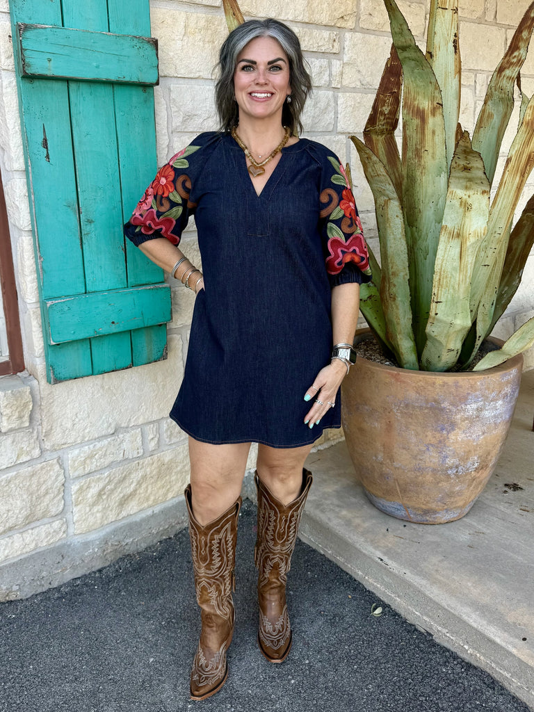 THS2066 — Women's dark navy denim mini shift dress with bold colorful floral embroidered elbow-length puff sleeves featuring large red, pink, burgundy, and green blooms with scrolling caramel vine motifs, V-neckline, ribbed elastic cuffs, and relaxed A-line silhouette — Blair's Western Wear Marble Falls TX
