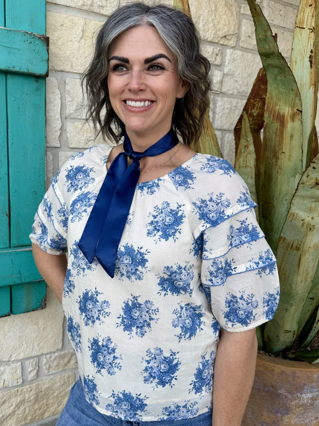 Women’s Ivy Jane blouse floral top in cream and blue, lightweight fabric with tiered puff sleeves and navy tie neckline - 641483. Available at Blair's Western Wear, Marble Falls, TX.