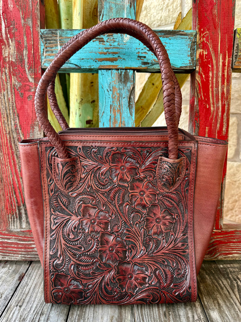 Women’s KBG tooled leather tote bag in brown, floral tooled genuine leather construction, with braided leather handles and secure top zipper closure – KBG338A. Available at Blair's Western Wear, Marble Falls, TX.
