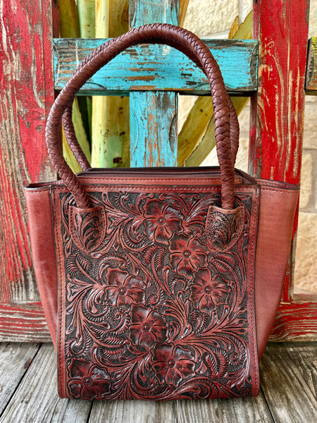 Women’s KBG tooled leather tote bag in brown, floral tooled genuine leather construction, with braided leather handles and secure top zipper closure – KBG338A. Available at Blair's Western Wear, Marble Falls, TX.