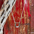 Women's Montana Silversmiths silver necklace in horseshoe pendant style, silver-tone finish with contrasting black inlay enhances depth and detail, with clear cubic zirconia stones set along the horseshoe for added sparkle - QNC6429. Available at Blair's Western Wear, Marble Falls, TX.