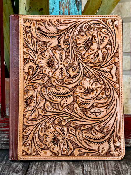 This stunning natural tan leather portfolio is jaw-dropping from the first glance — completely covered in deep hand-carved floral, poppy, and scroll tooling with dark brown antiqued contrast, dark brown leather spine, and American Darling brand stamp on the front — Blair's Western Wear Marble Falls TX