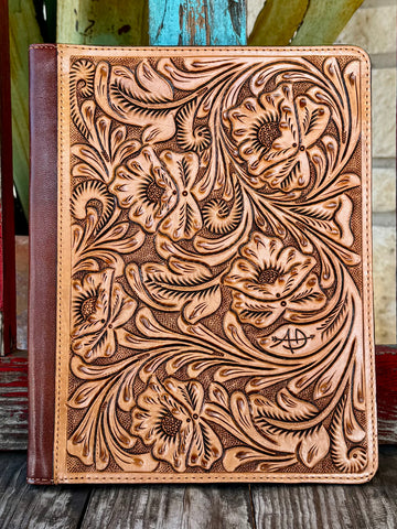 This stunning natural tan leather portfolio is jaw-dropping from the first glance — completely covered in deep hand-carved floral, poppy, and scroll tooling with dark brown antiqued contrast, dark brown leather spine, and American Darling brand stamp on the front — Blair's Western Wear Marble Falls TX