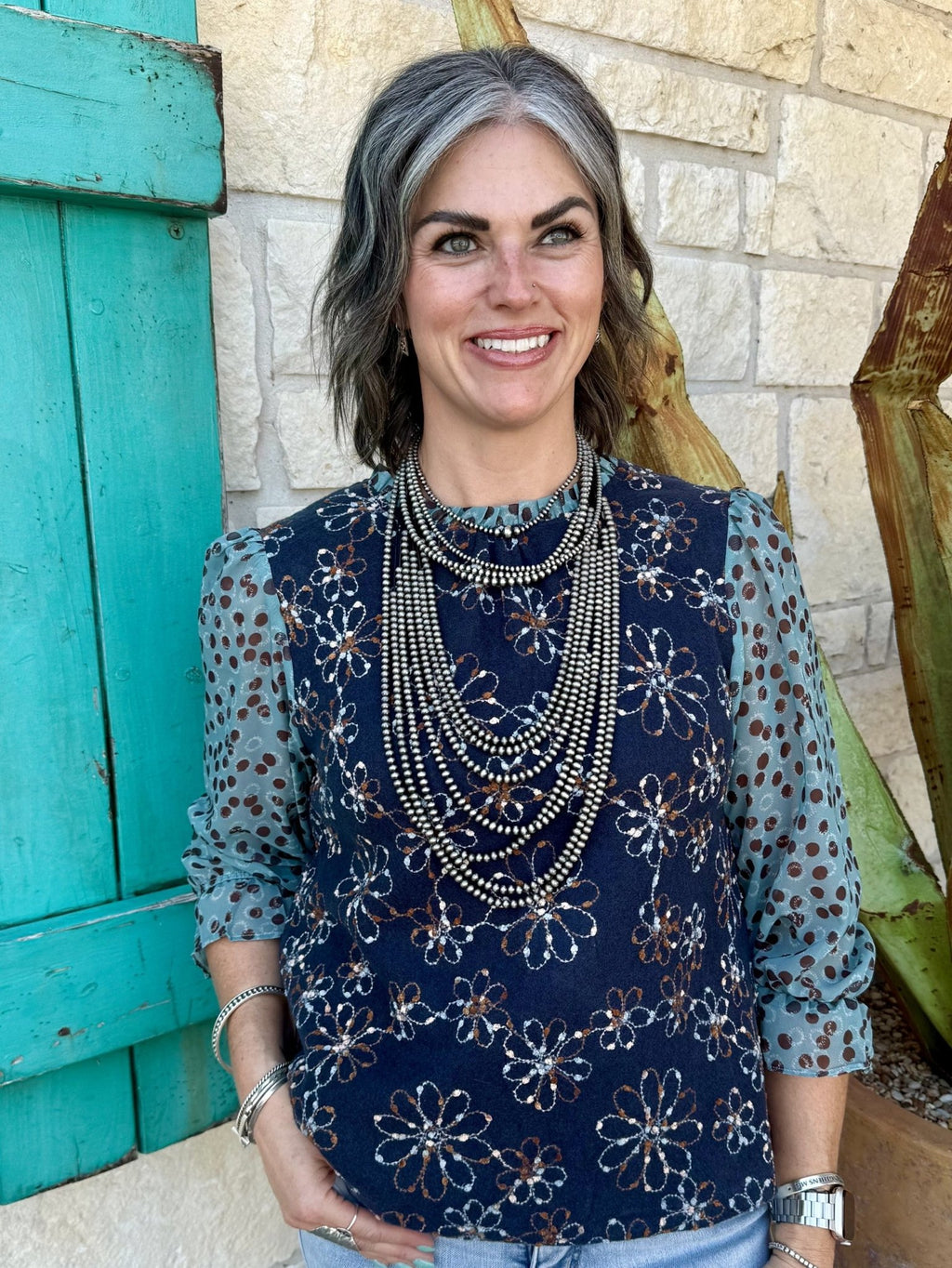 37183V — Full-length view of women's navy floral embroidered mixed media long sleeve top showing navy embroidered knit body, sheer sage dot-print chiffon sleeves with gathered cuffs, and relaxed fit — Blair's Western Wear Marble Falls TX