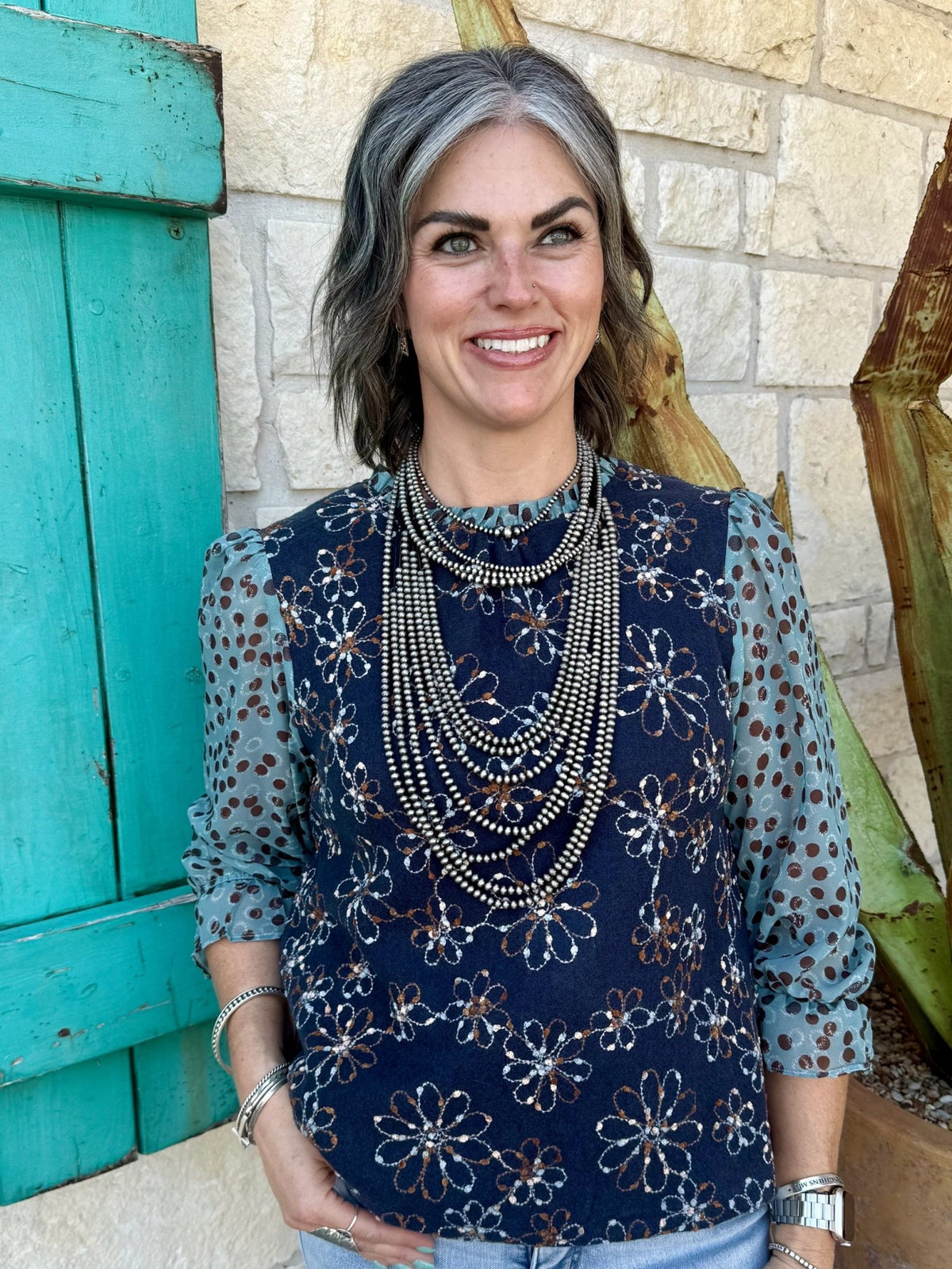 37183V — Full-length view of women's navy floral embroidered mixed media long sleeve top showing navy embroidered knit body, sheer sage dot-print chiffon sleeves with gathered cuffs, and relaxed fit — Blair's Western Wear Marble Falls TX