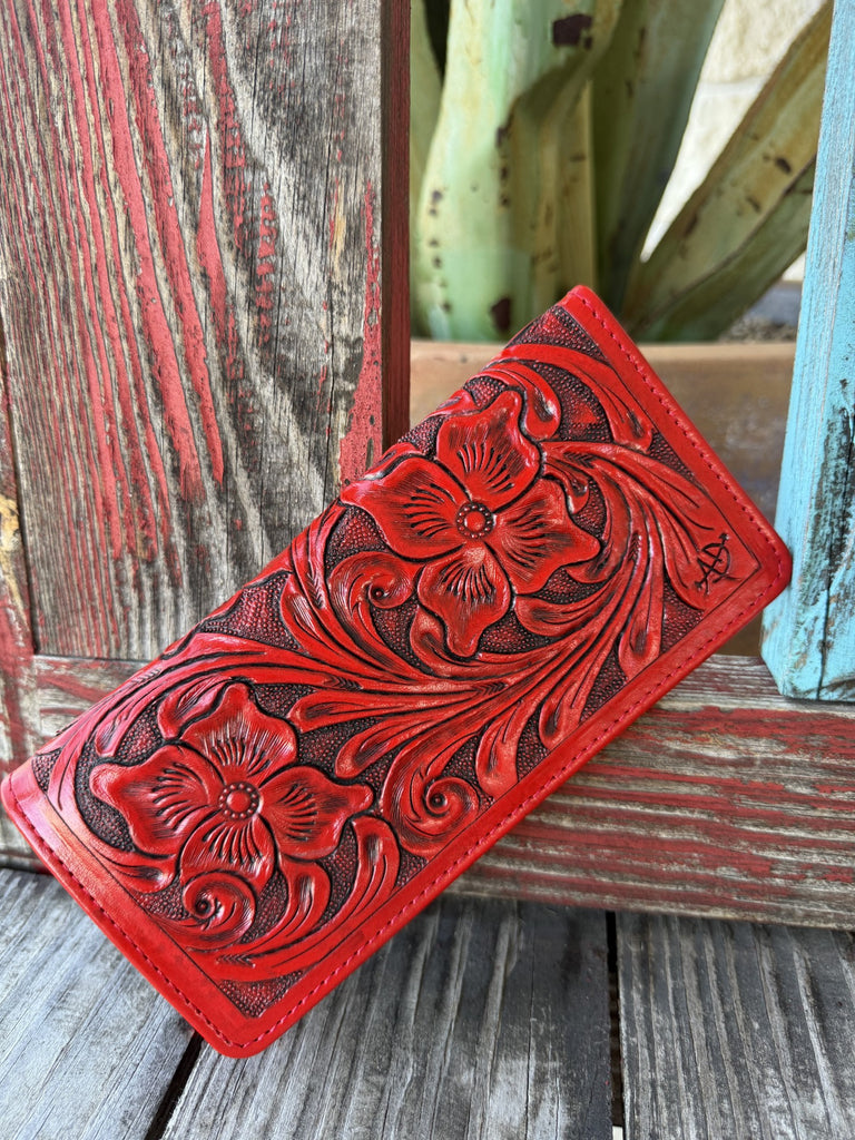 Women's red hand-tooled leather zip wallet with deep floral and scroll carving and dark antiqued finish, angled front view — Blair's Western Wear Marble Falls TX