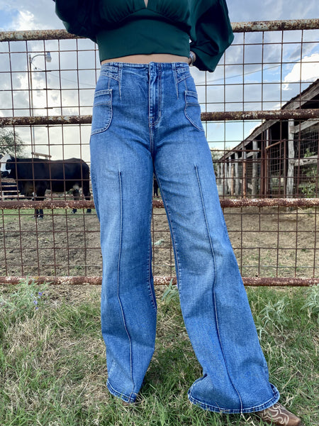 Women's Rock 'n' Roll Denim high rise palazzo flare jean RRWD8HROSJ front view showing curved front seam stitching, wide flare leg, and high-rise waistband styled with teal crop top and western boots — Blair's Western Wear Marble Falls TX