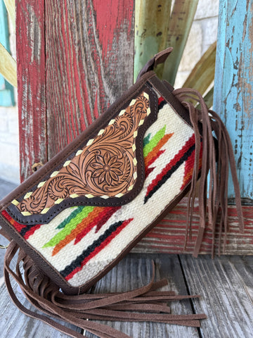 Women's crossbody purse with hand-tooled floral leather envelope flap, Aztec-inspired serape woven body in cream, red, green, and orange, and brown leather fringe — Blair's Western Wear Marble Falls TX