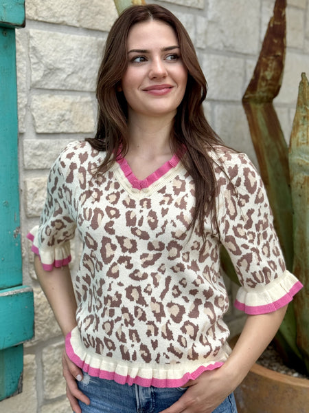Women's natural tan and pink leopard print knit top with V-neck and pink trim, styled with wide-leg jeans — Blair's Western Wear Marble Falls TX