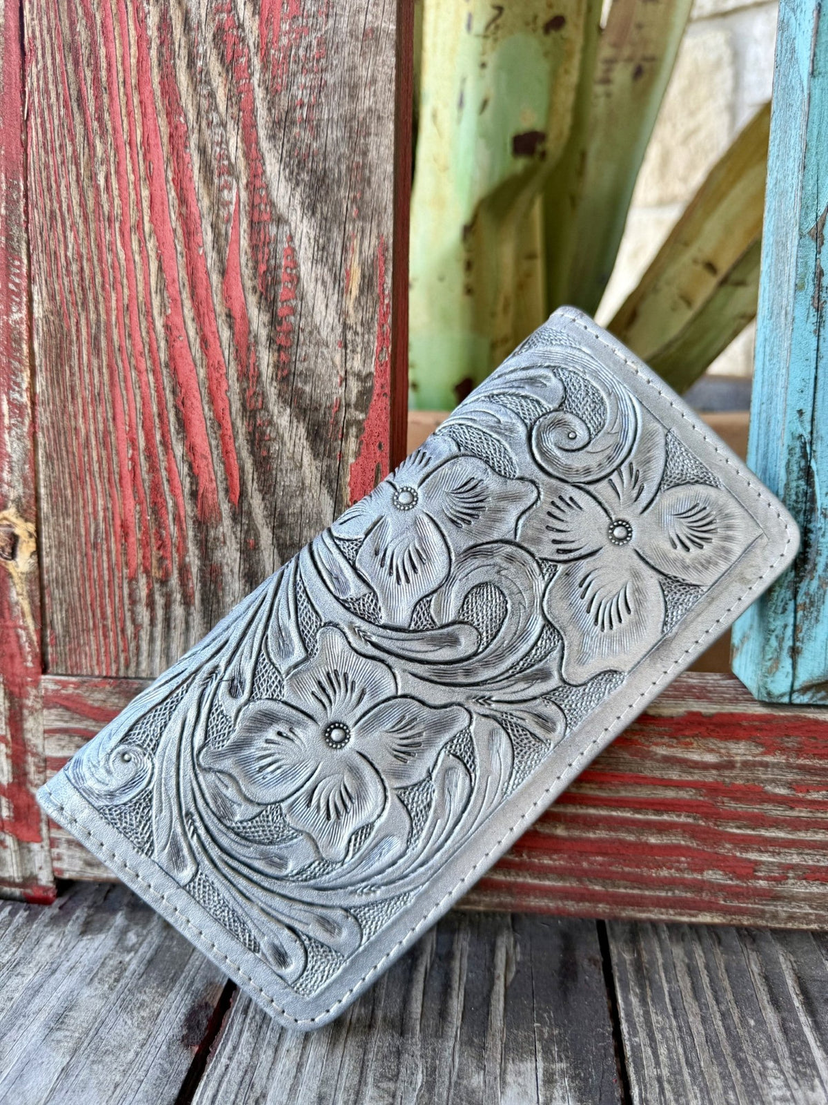 Women's metallic silver hand-tooled leather zip wallet with deep floral and scroll tooling across full exterior, front view — Blair's Western Wear Marble Falls TX