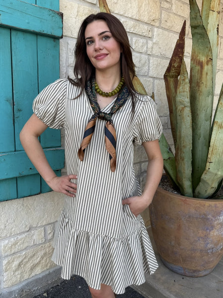 Women's natural and olive ticking stripe V-neck dress with puff sleeves, ruffle hem, and pockets, styled with wild rag and green bead necklace — Blair's Western Wear Marble Falls TX