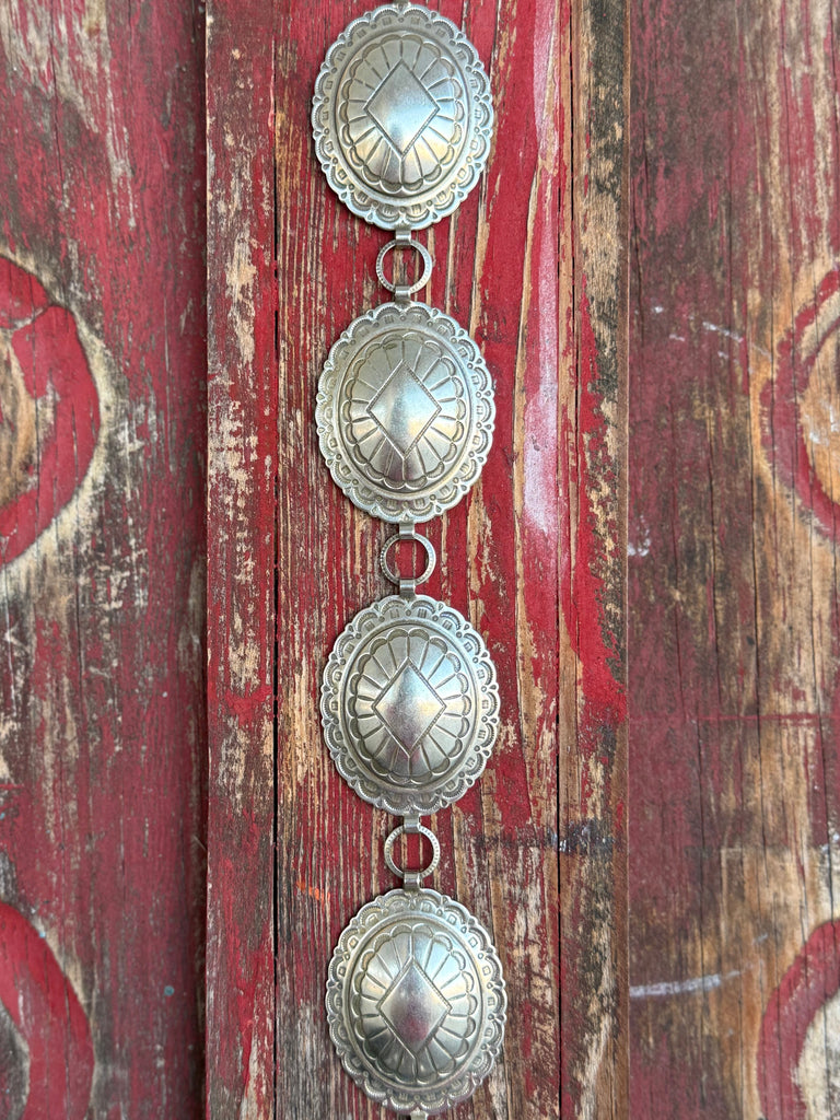 Make a lasting impression with this stunning Sunwest concho belt. Oval-linked conchos showcase intricate stamped Southwestern-inspired patterns, delivering that authentic Western artistry you can feel as much as see — beautifully crafted and endlessly wearable.