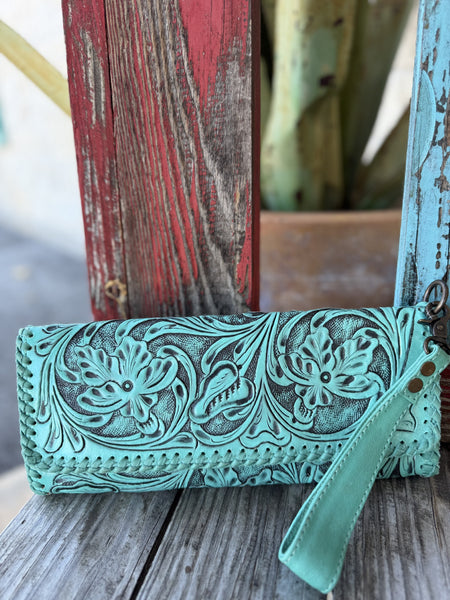 This stunning turquoise hand-tooled leather wristlet clutch is pure western artisan magic — deep floral and scroll carving with rich dark antiqued contrast, punched hole edge detailing, and a turquoise leather wrist strap with gunmetal hardware — Blair's Western Wear Marble Falls TX