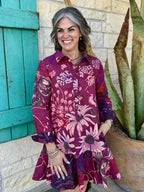 72688 — Women's deep wine burgundy oversized floral linen swing shirt dress with large pink dahlias, echinacea, and hydrangea botanical print, point collar, button-front placket, long sleeves with button cuffs, drop-waist silhouette, and dramatically flared swing skirt, styled with tall brown western boots — Blair's Western Wear Marble Falls TX