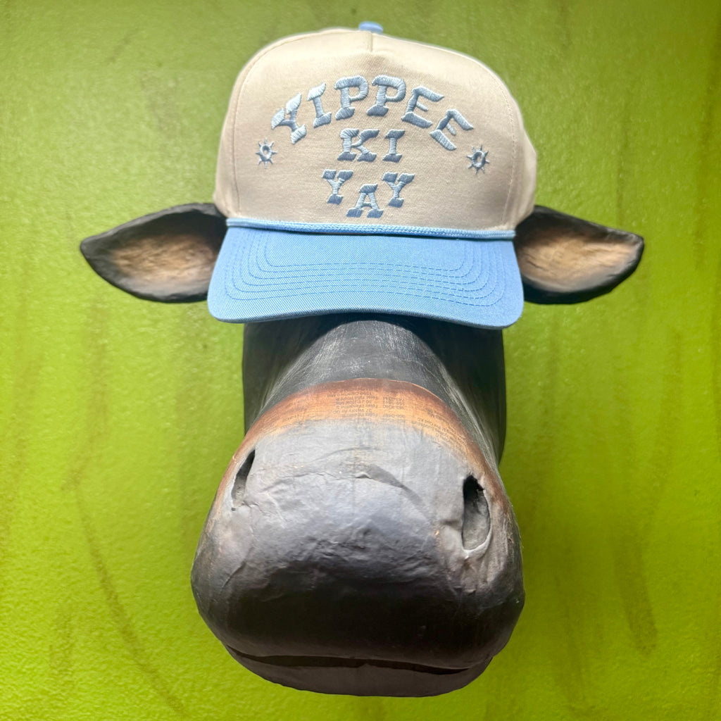 Yippee Ki Yay Trucker Cap in Light Tan/Blue, structured foam front panel, with breathable mesh back and embroidered text - YIPPEELTB. Available at Blair's Western Wear, Marble Falls, TX.