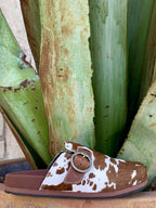  Women's brown and white hair-on-hide cowhide slip-on mule with silver O-ring Ariat buckle strap, round toe, and contoured brown footbed — Blair's Western Wear Marble Falls TX