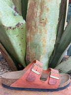 Women's burnt-orange oiled leather two-strap sandal with adjustable metal buckles and a cushioned cork footbed — Blair's Western Wear Marble Falls TX⠋