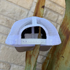 A white trucker-style cap viewed from the back, featuring a white mesh back and a white plastic snap closure