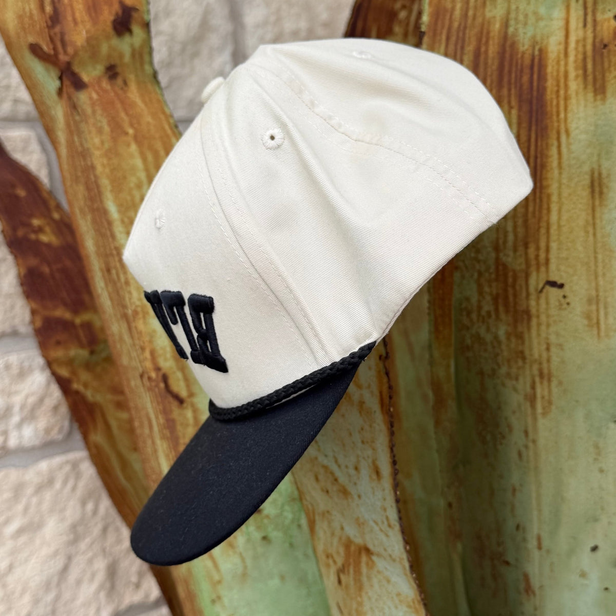An off-white baseball cap with a black visor and black embroidered lettering on the front