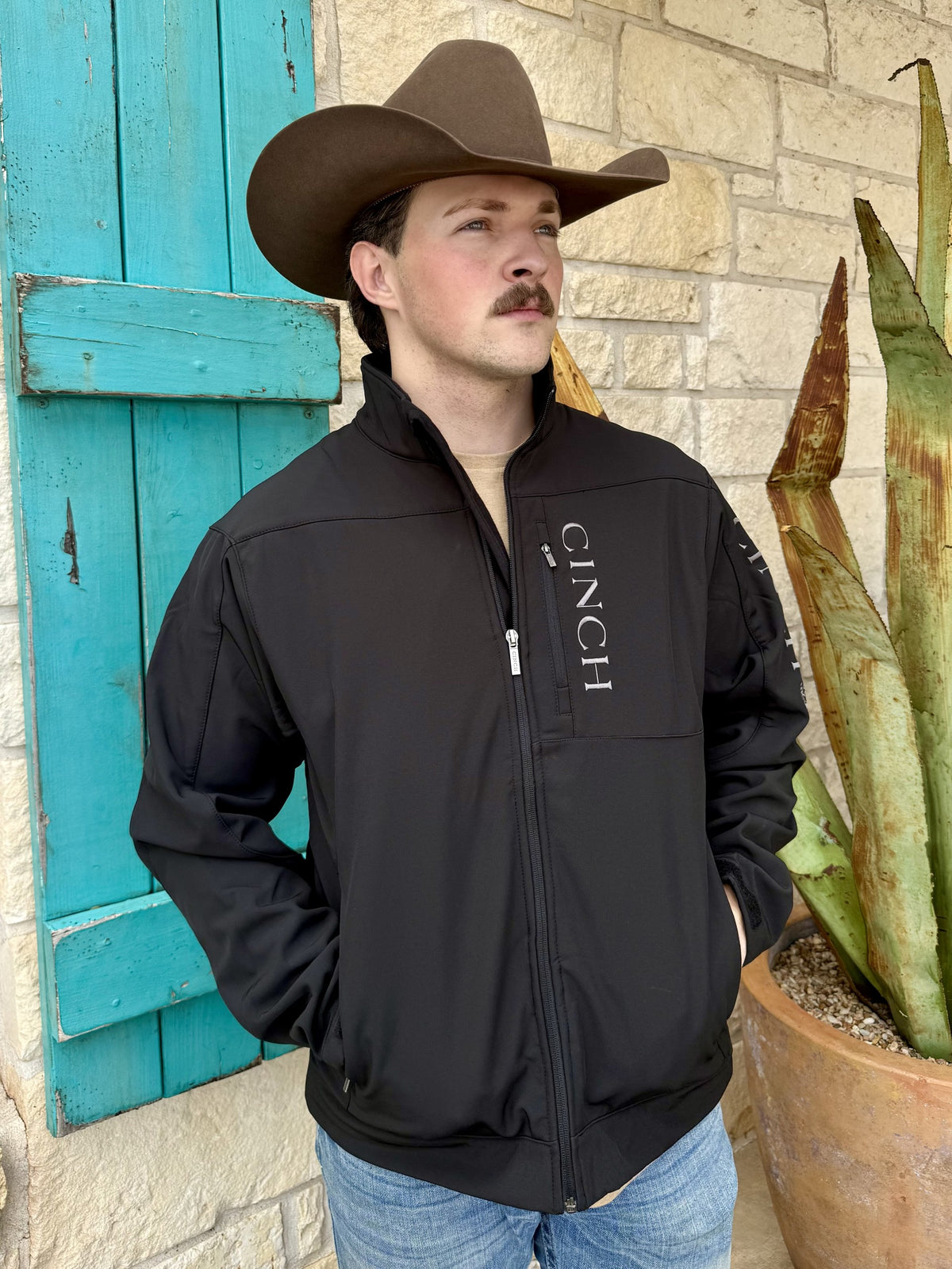 Men's black bonded jacket with stand collar, full zip-front closure, vertical zippered chest pocket, side pockets, long sleeves, and contrasting embroidered logos — Blair's Western Wear Marble Falls TX