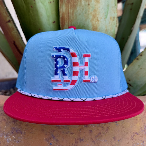 Men's red and light blue mesh trucker cap with embroidered Red Dirt Hat Co. logo in American flag red, white, and blue pattern — Blair's Western Wear Marble Falls TX