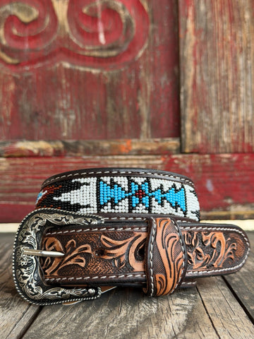 Dark leather is hand-tooled with golden floral scrollwork and inlaid with a vivid Aztec-inspired beaded stripe in cobalt blue, burgundy, and white — finished with an ornate engraved silver buckle for a bold southwestern statement. Available at BLAIR'S Western Wear located in Marble Falls TX 