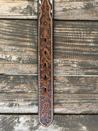 Kid's Aztec-Inspired Embroidered Cross Belt Black leather strap with a multicolor Aztec-inspired embroidered cross panel in teal, orange/red, olive/gold, and white. White lace whipstitch edge detail flanks the embroidered panel. Cognac floral scroll-tooled leather keeper loop. Large oval silver buckle with 3D bucking bronco and rider centerpiece, ornate floral scroll engraving, and beaded rope border. Available at Blair's Western Wear, Marble Falls, TX