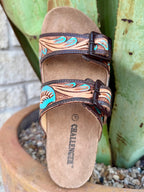 Women’s Tackrus Sandal Tooled Leather Slide in Natural, hand-tooled full-grain leather straps with turquoise floral accents, with contoured suede footbed and cork midsole – 25JQ105. Available at Blair's Western Wear, Marble Falls, TX.