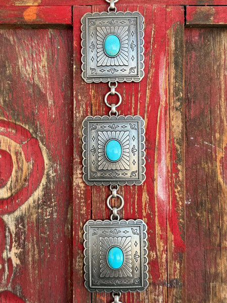 Ladies M & F Western concho belt in silver with turquoise stones, featuring scalloped square conchos and adjustable chain links for a perfect fit – A1567433. Available at Blair’s Western Wear, Marble Falls, TX.