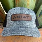 A heather gray trucker hat with black mesh side panels and a brown leather patch on the front that reads ARIAT, 