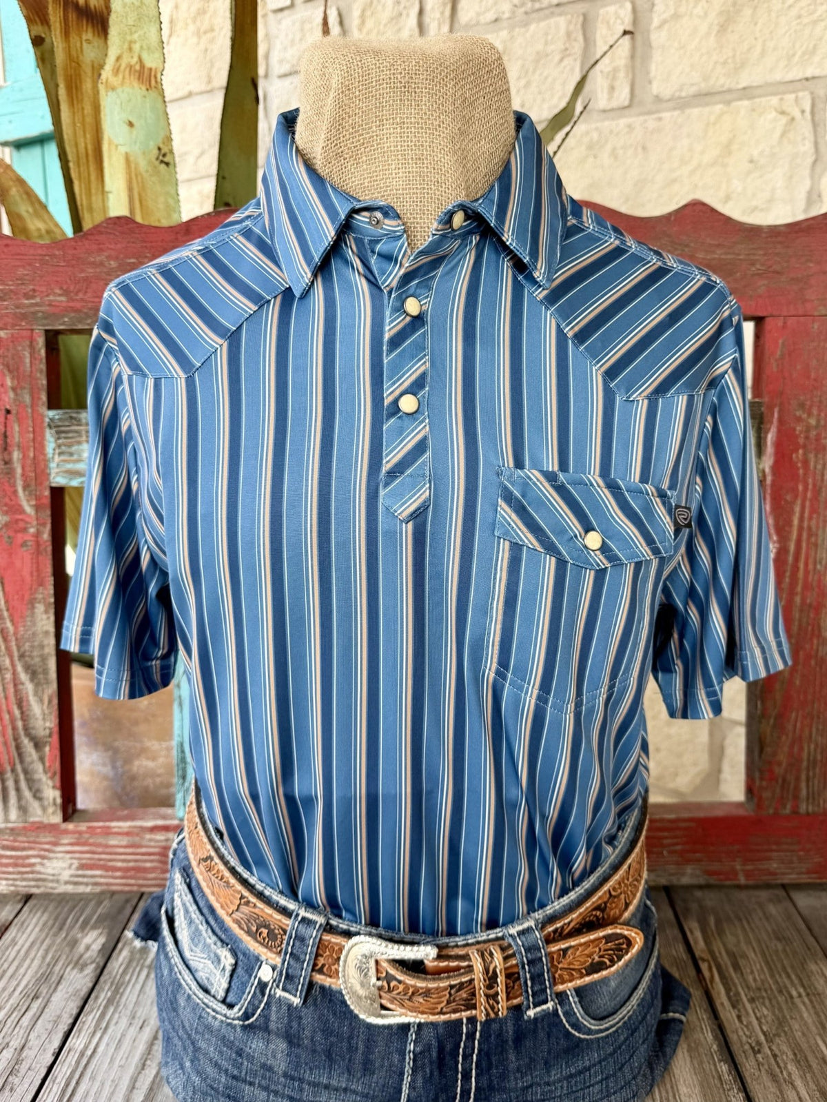 Men's blue short-sleeve pullover shirt with narrow tan and white vertical stripes, pointed collar, partial snap placket, angled Western yokes and a snap-flap chest pocket — Blair's Western Wear Marble Falls TX