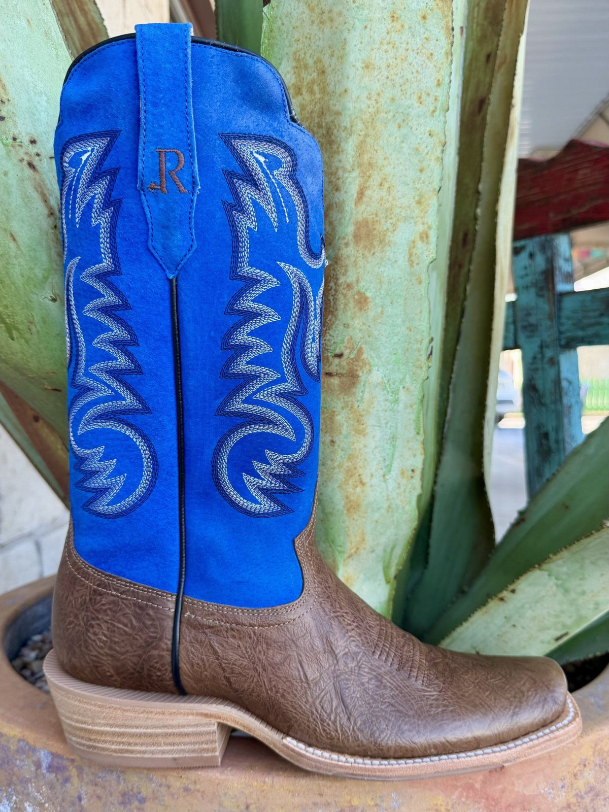 Side view of brown textured Western boot with vivid blue stitched shaft, blue logo pull tab and blunt toe — Blair's Western Wear Marble Falls TX