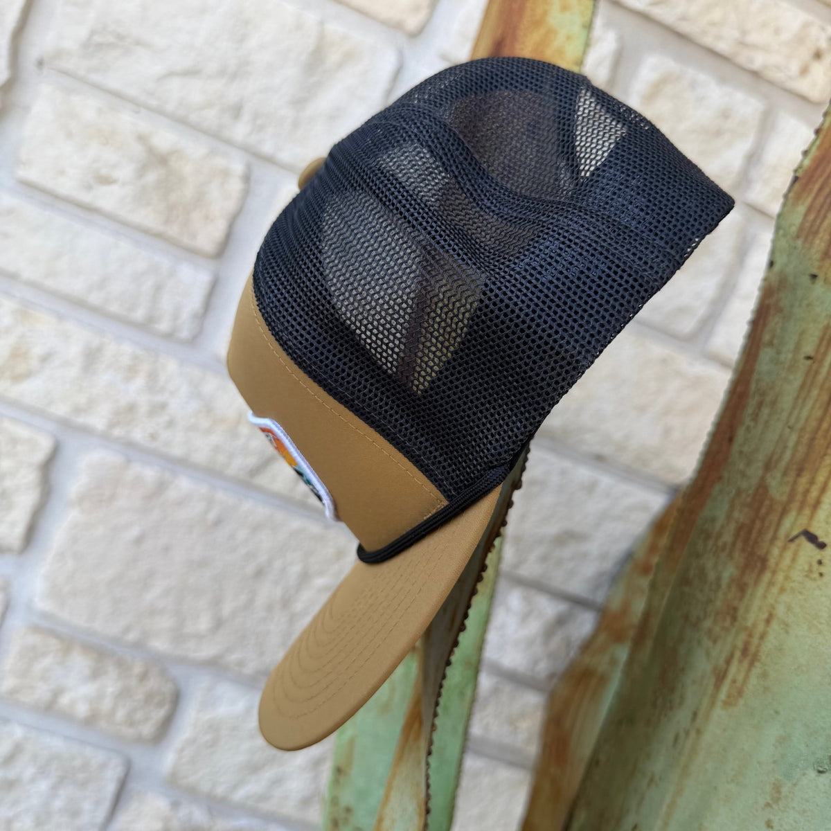 A tan and black trucker hat with a black mesh back