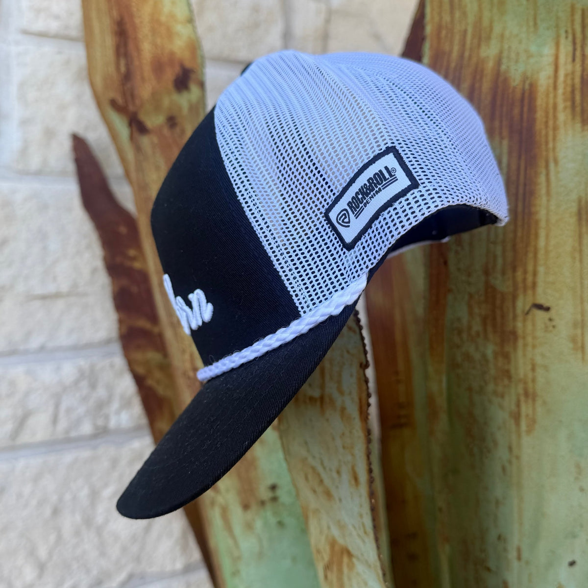 A black and white cap with a white mesh back, black visor, and a white braided trim