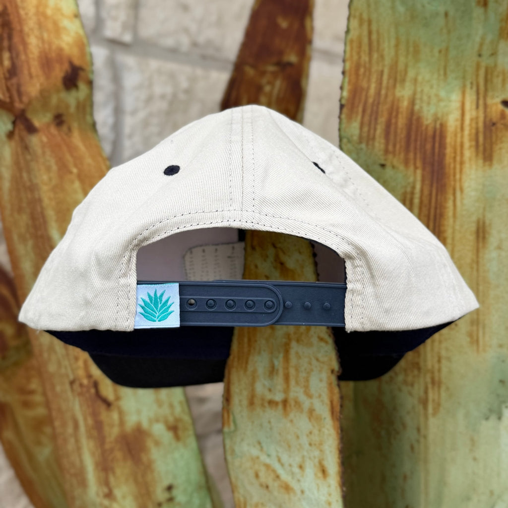 A light beige structured cap with a dark navy adjustable strap and a small Sendero logo patch