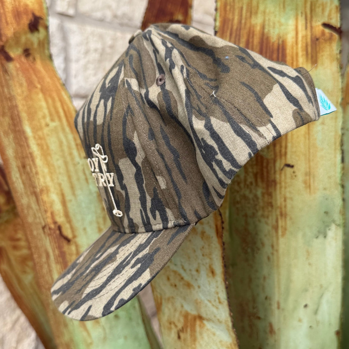 A cap with a camouflage pattern, featuring a beige embroidered logo on the front 