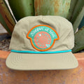 A khaki-colored cap with a turquoise and orange embroidered patch that reads 'Keepin' it reel' on the front, 