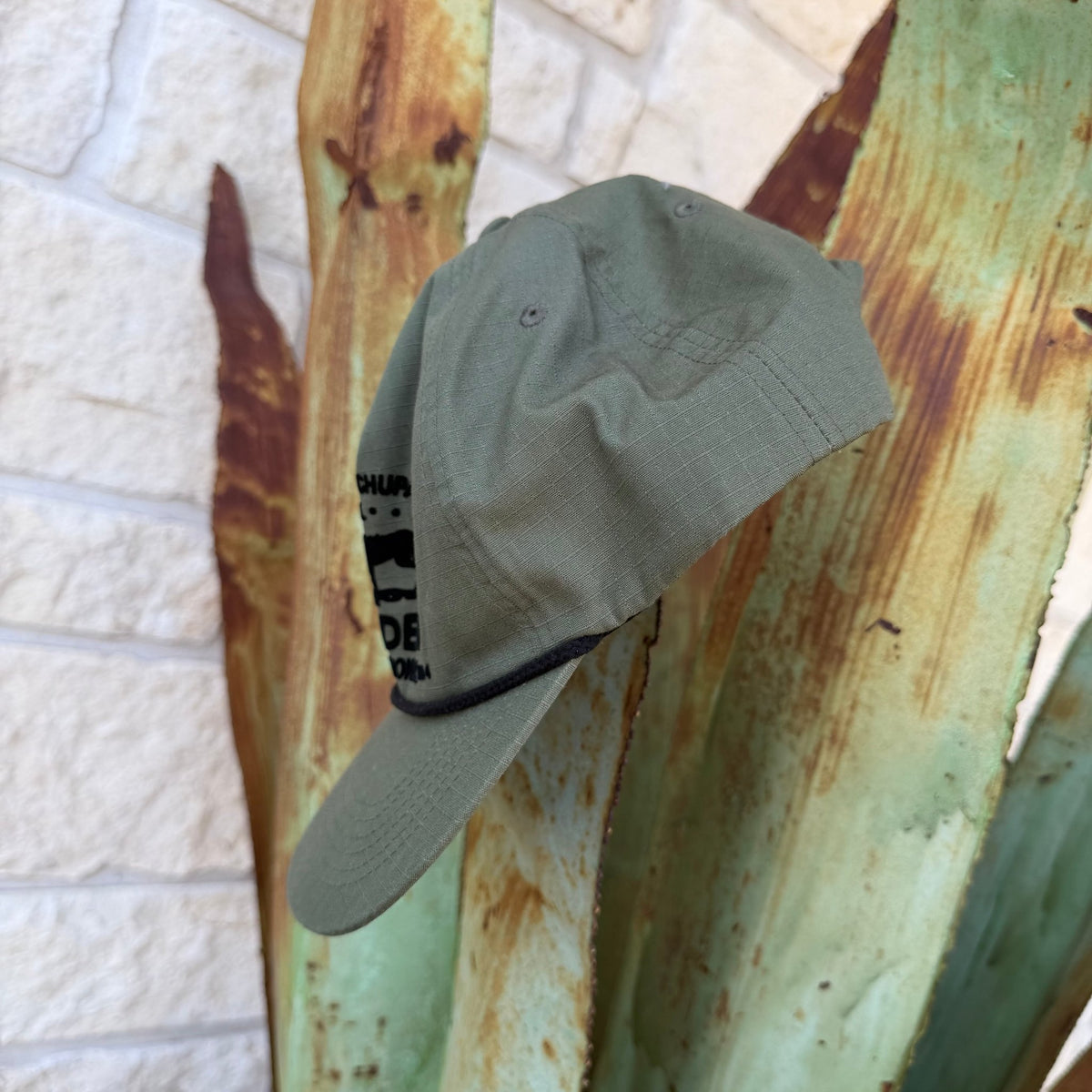 An olive green cap with black text on the side,