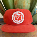 An orange flat-brim cap with a circular white patch featuring an orange wild cat graphic and the text 'GHOSTS OF THE DESERT' and 'SENDERO PROVISIONS CO.'