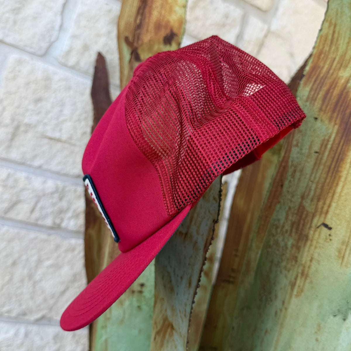 A red cap with a solid red front panel and visor, and a red mesh back
