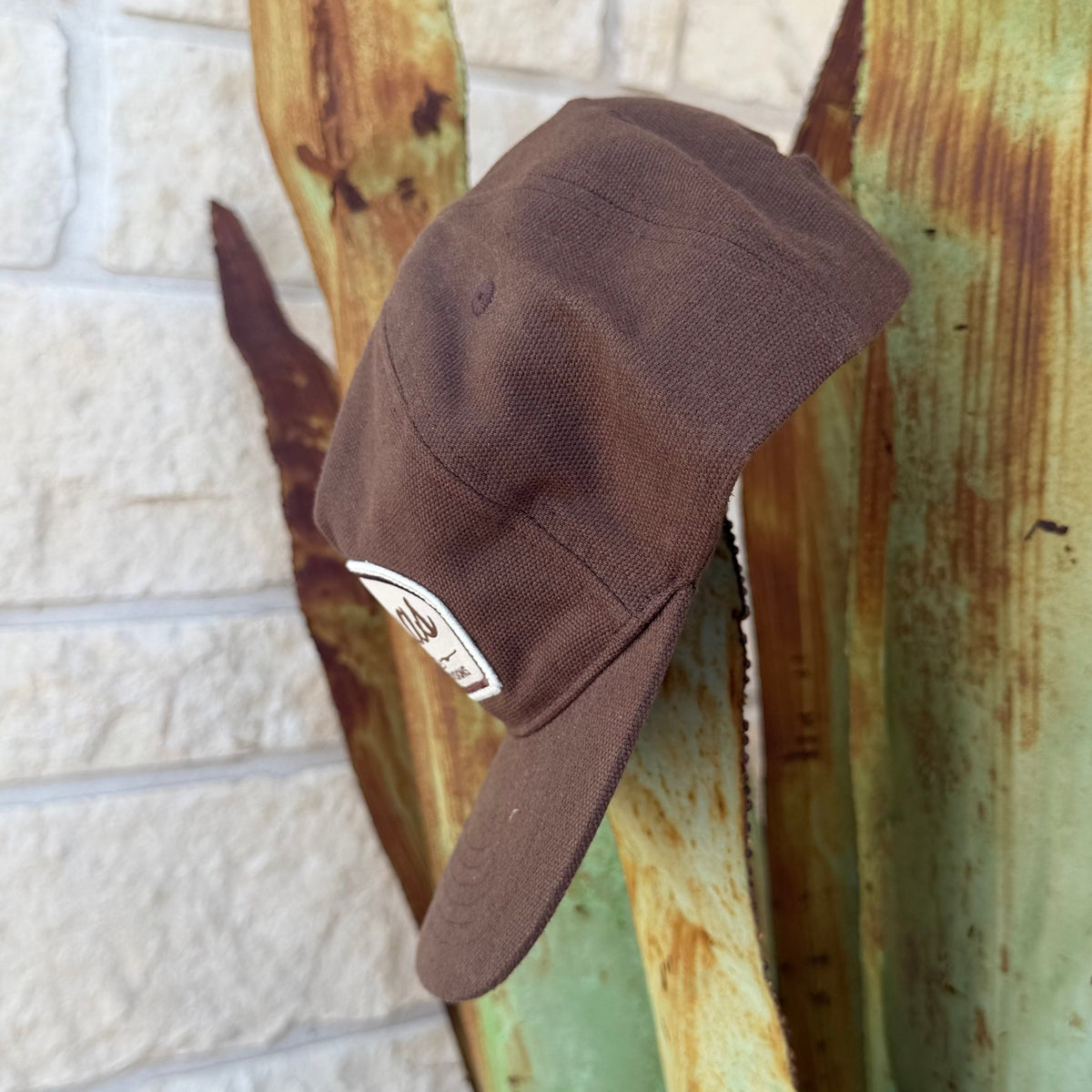 A brown cotton  cap with a white rectangular patch on the side