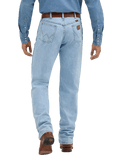 Rear view of a person wearing light-wash blue denim jeans with a brown belt and brown boots, against a plain white studio background.