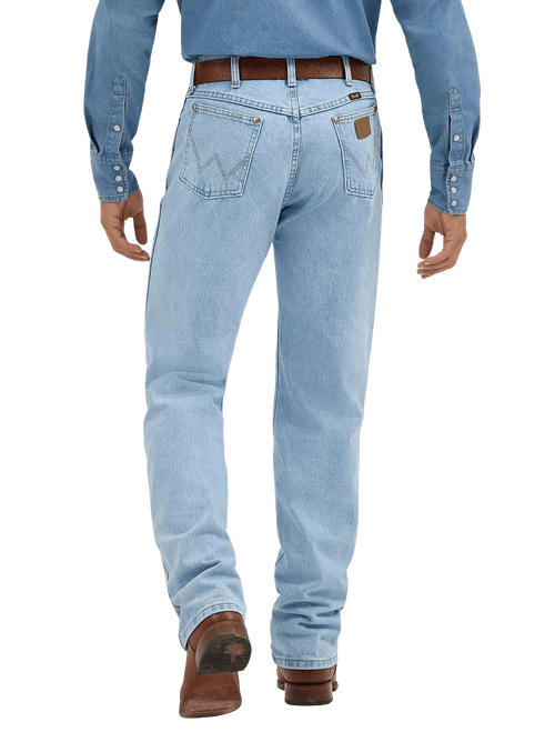 Rear view of a person wearing light-wash blue denim jeans with a brown belt and brown boots, against a plain white studio background.