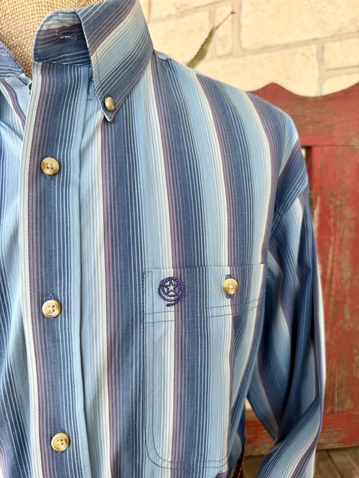 Close-up of men's blue striped shirt showing fine vertical lines, button-down collar, and single chest pocket with embroidered emblem — Blair's Western Wear Marble Falls TX