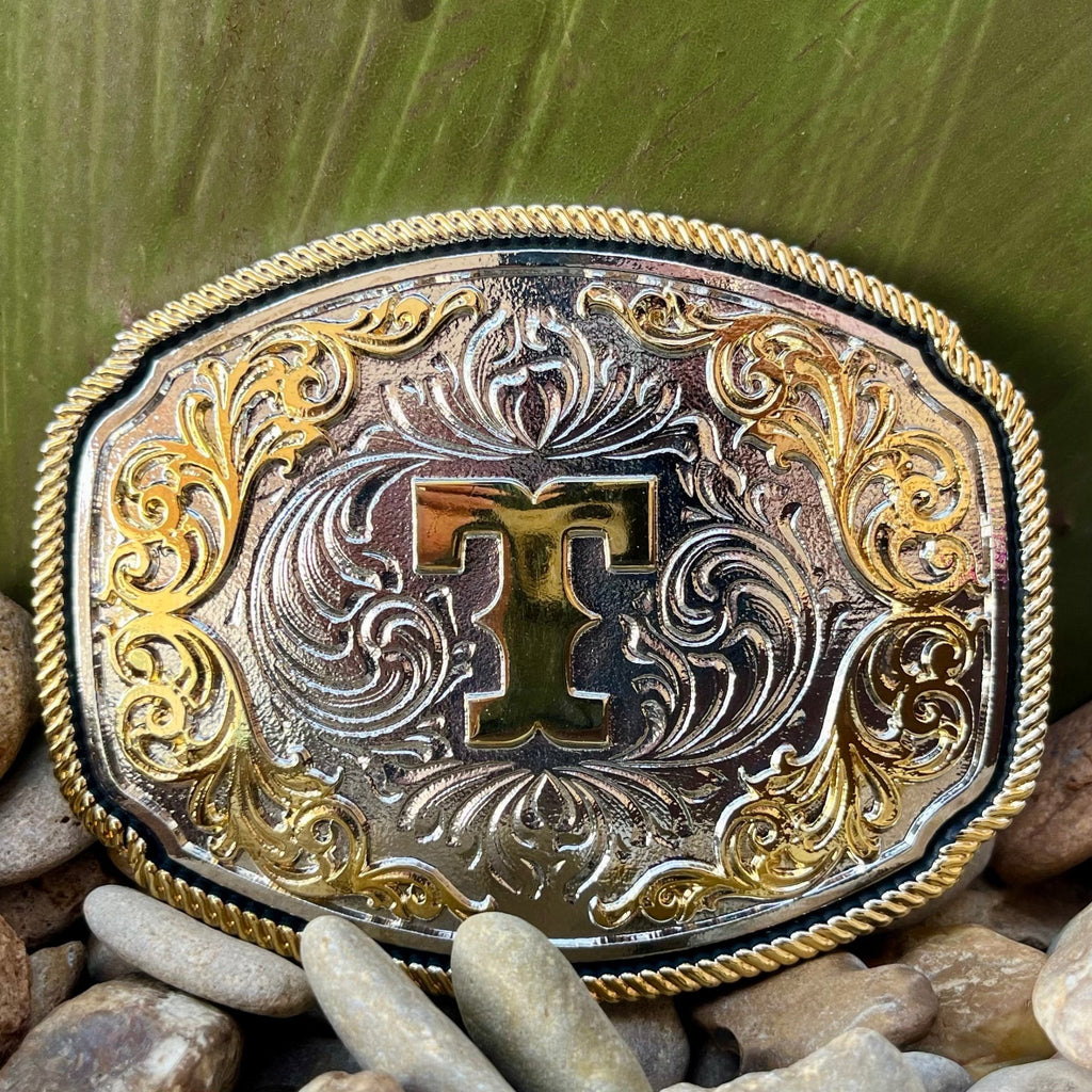 Montana Silversmiths Western Belt Buckle in silver and gold, featuring intricate engravings and a prominent 'T' initial - A1047T. Available at Blair's Western Wear, Marble Falls, TX.