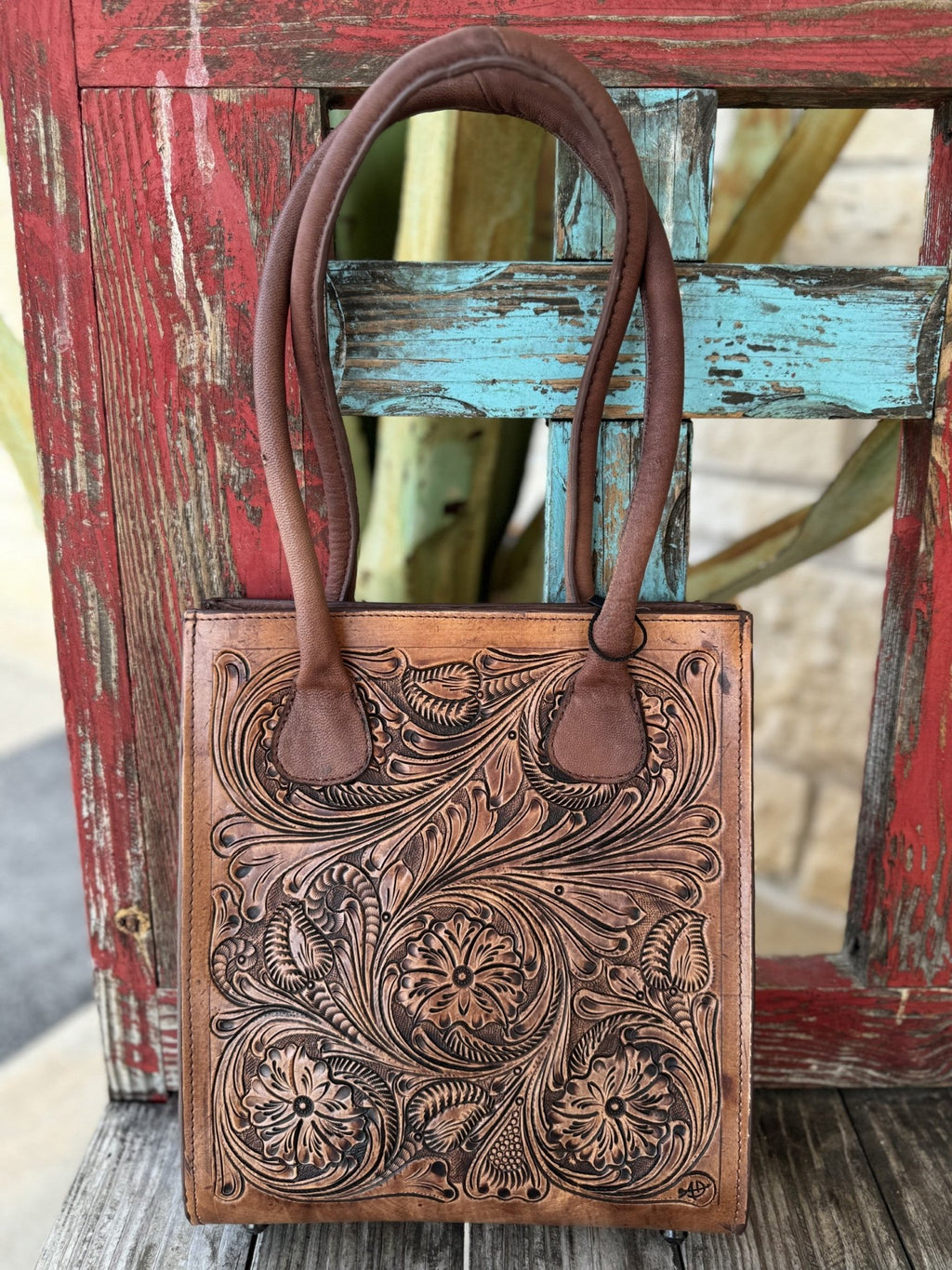 ADBGZ456 — Women's rich tan genuine leather structured tote purse with deep full-coverage floral and scroll hand-tooling, large central daisy/sunflower motif with sweeping acanthus leaf scrollwork and dark brown antiqued contrast, and two sturdy dark brown rounded loop leather top handles — Blair's Western Wear Marble Falls TX