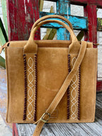 ADBGA605 — Women's golden tan/camel suede structured tote with two vertical dark brown whipstitch leather trim strips and cream/white diamond lattice cross-stitch embroidery on the front panel, two rounded suede top handles, adjustable tan suede crossbody strap with antique gold buckle, top zipper closure, and embossed American Darling logo patch — Blair's Western Wear Marble Falls TX