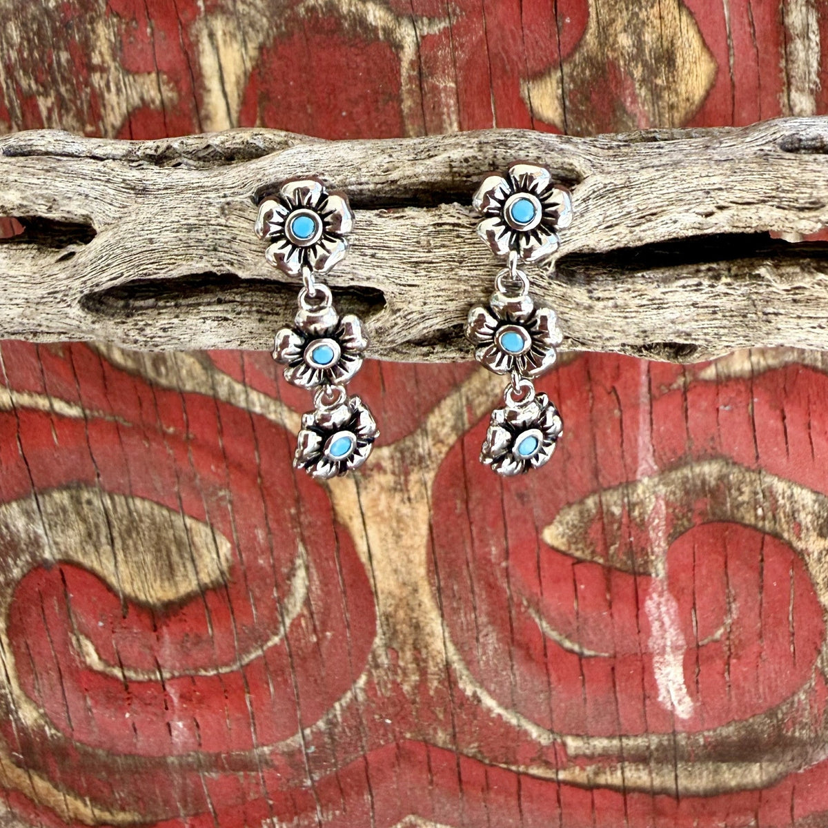 Women's silver-tone drop earrings with three linked flowers, sculpted petals, dark recessed detailing, and round turquoise-colored centers — Blair's Western Wear Marble Falls TX